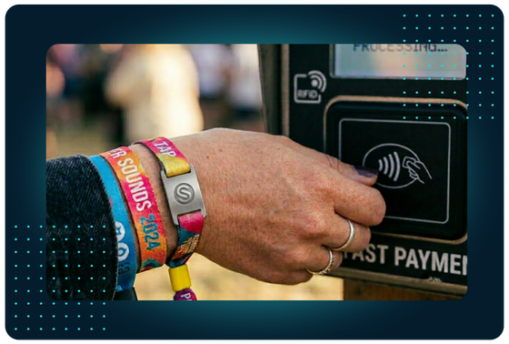 Festival-goer tapping an RFID wristband on a contactless reader, representing FaciliPay cashless solutions for festivals and events.